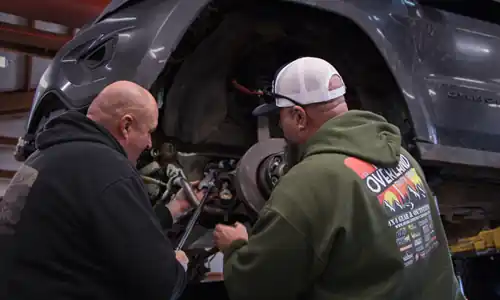 Technicians working on vehicle suspension and drivetrain